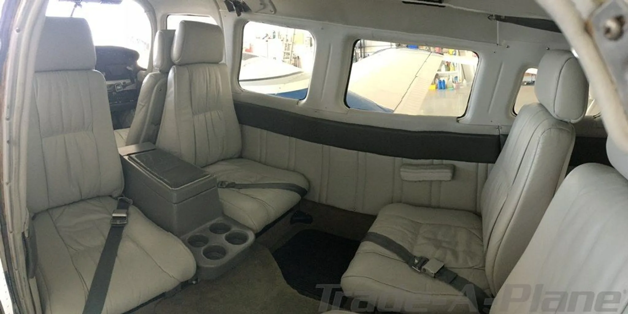 The aircraft's light gray interior cabin with multiple seats and a center console, viewed from the rear.