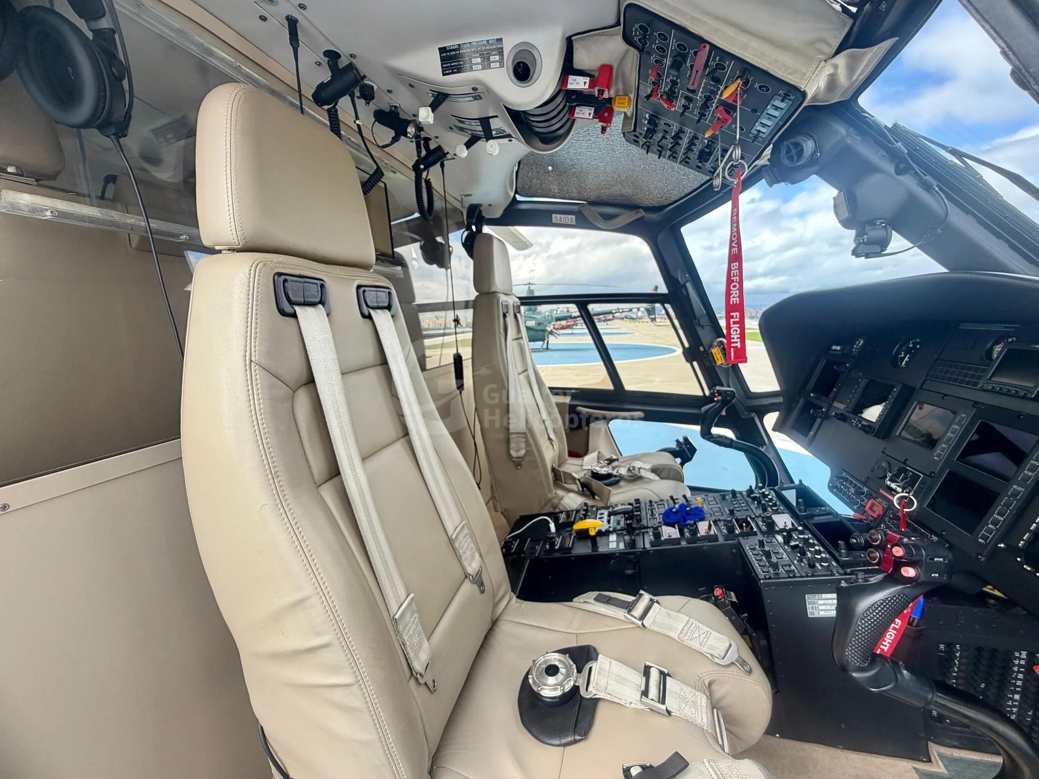 View from the co-pilot's seat showing the cockpit controls and beige leather seats.