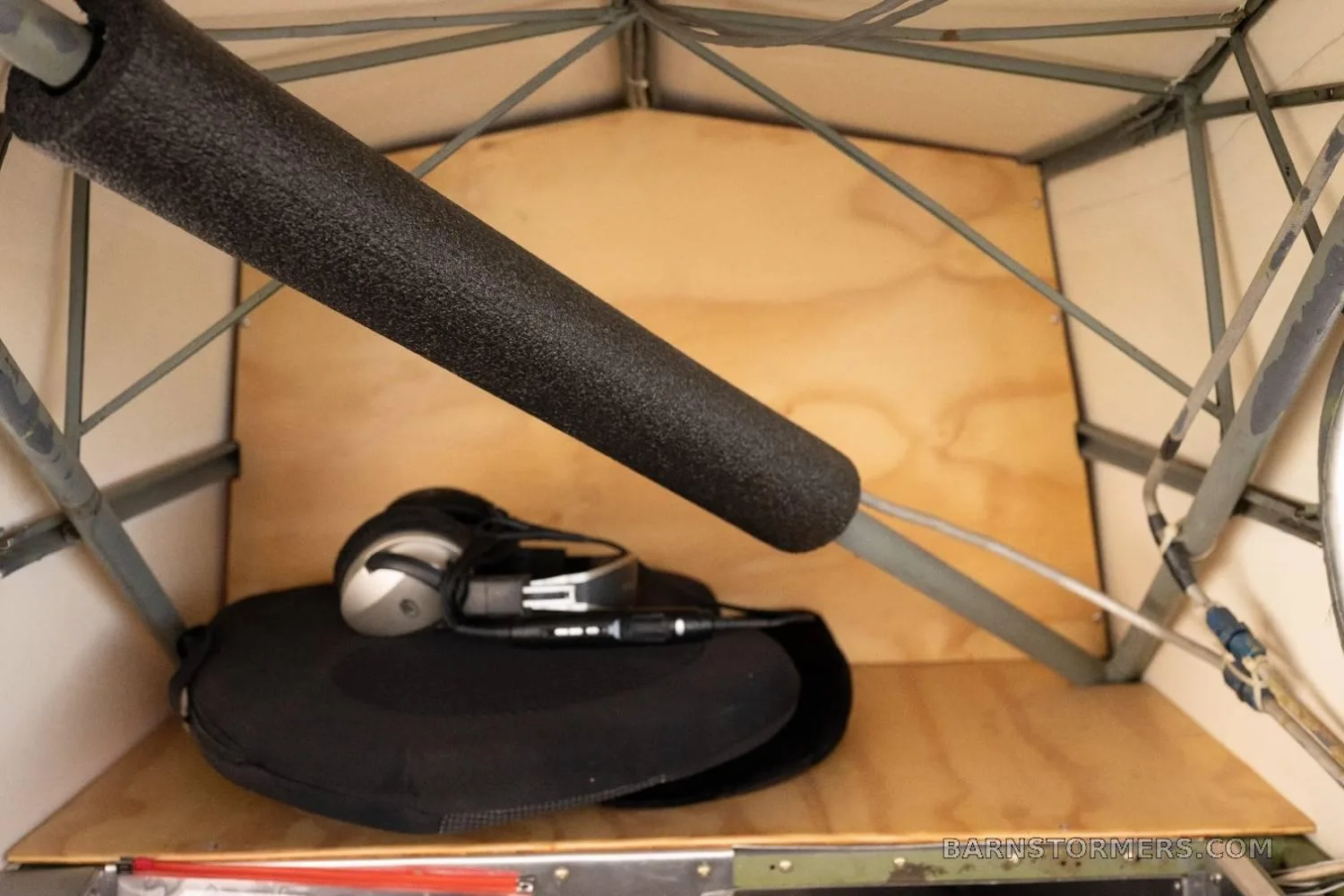 A view of the aircraft's rear storage compartment with a headset and a black bag.