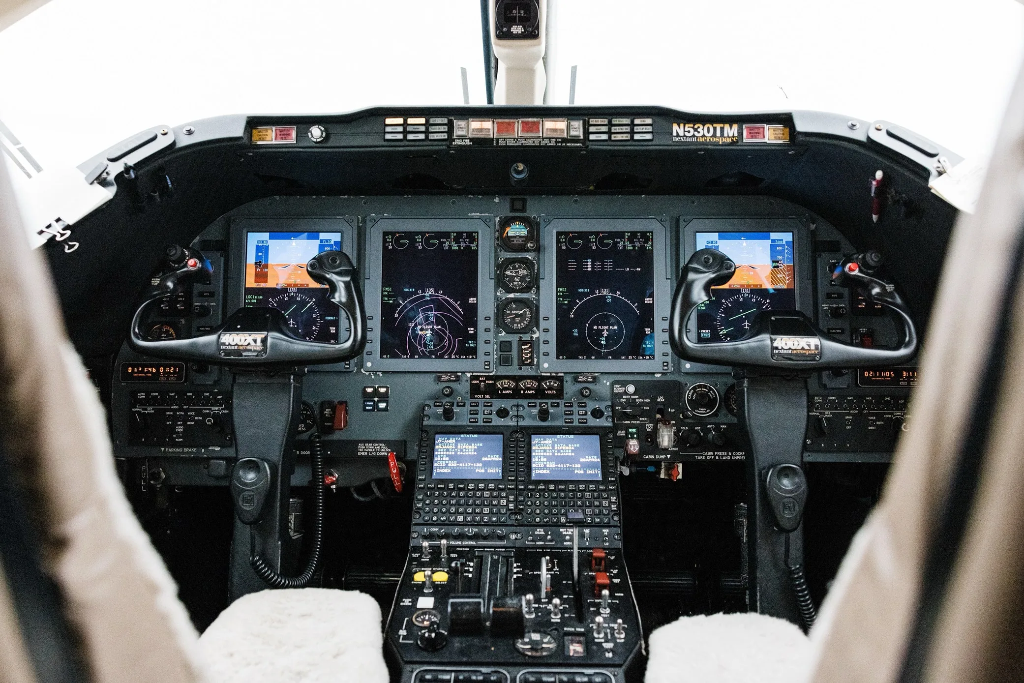 The cockpit of the private jet, featuring multiple digital displays and control panels.