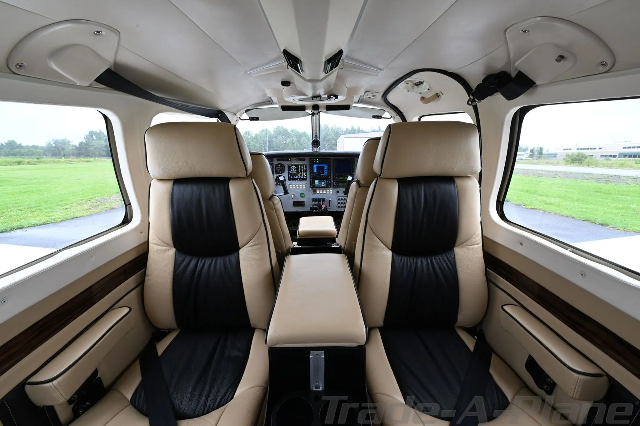 The tan and black leather interior of a Piper Saratoga cabin, looking forward towards the cockpit.