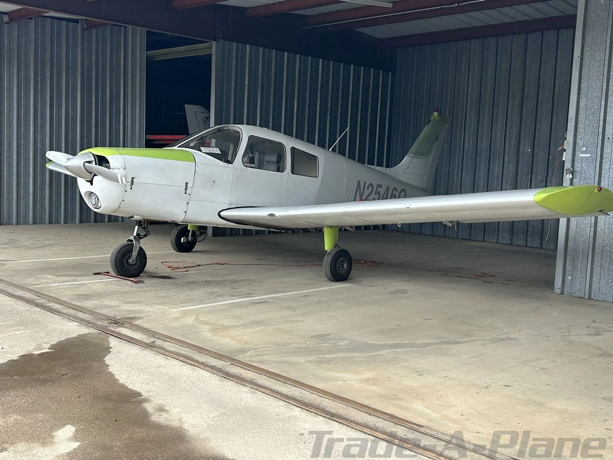 A light gray single-engine aircraft with lime green accents, registration N2546Q, parked in a hangar, viewed from the front-left.