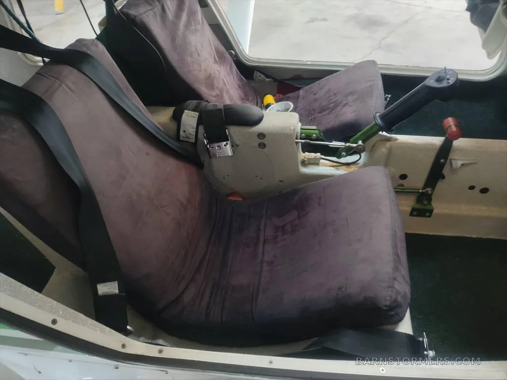 The two dark grey fabric seats and controls inside the cabin of a light aircraft.