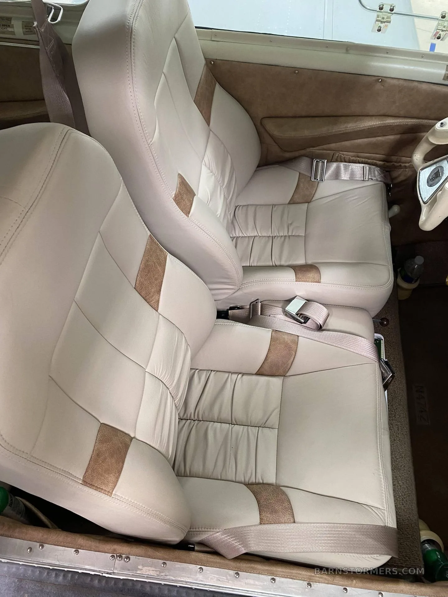 The light beige and brown quilted leather seats of an aircraft interior are shown.