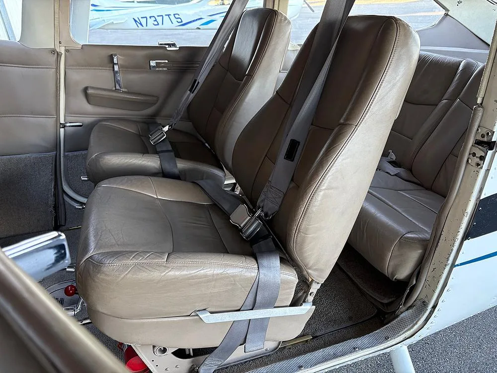 The tan leather front and rear passenger seats with seatbelts inside a small aircraft.