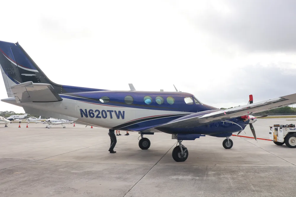 A blue and white twin-engine turboprop aircraft, N620TW, being towed on a tarmac.