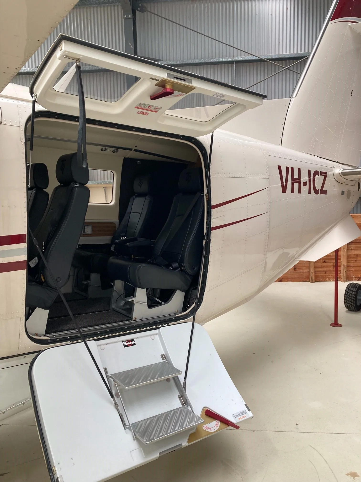 The rear cargo door of a beige Quest Kodiak 100 aircraft, registration VH-ICZ, open to reveal the passenger seats inside.