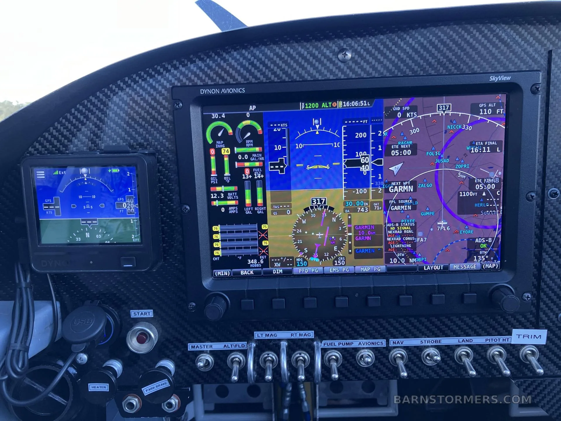 A close-up view of the aircraft's carbon fiber instrument panel featuring a large Dynon SkyView display and various switches.
