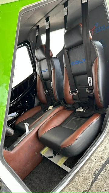 The two-tone brown and black leather seats of a Colt light sport aircraft interior, with harnesses.