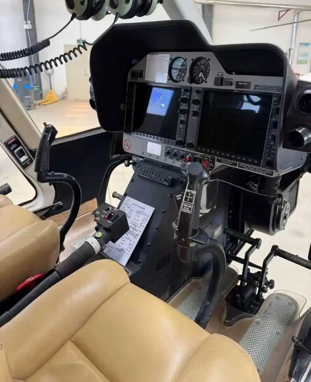 The cockpit of a Bell 407GXP helicopter features dual display screens and tan leather pilot seats.