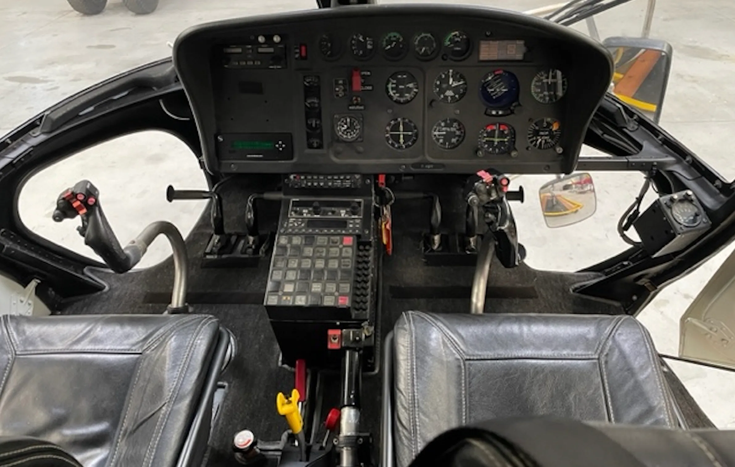 Helicopter cockpit with analog instruments and controls.