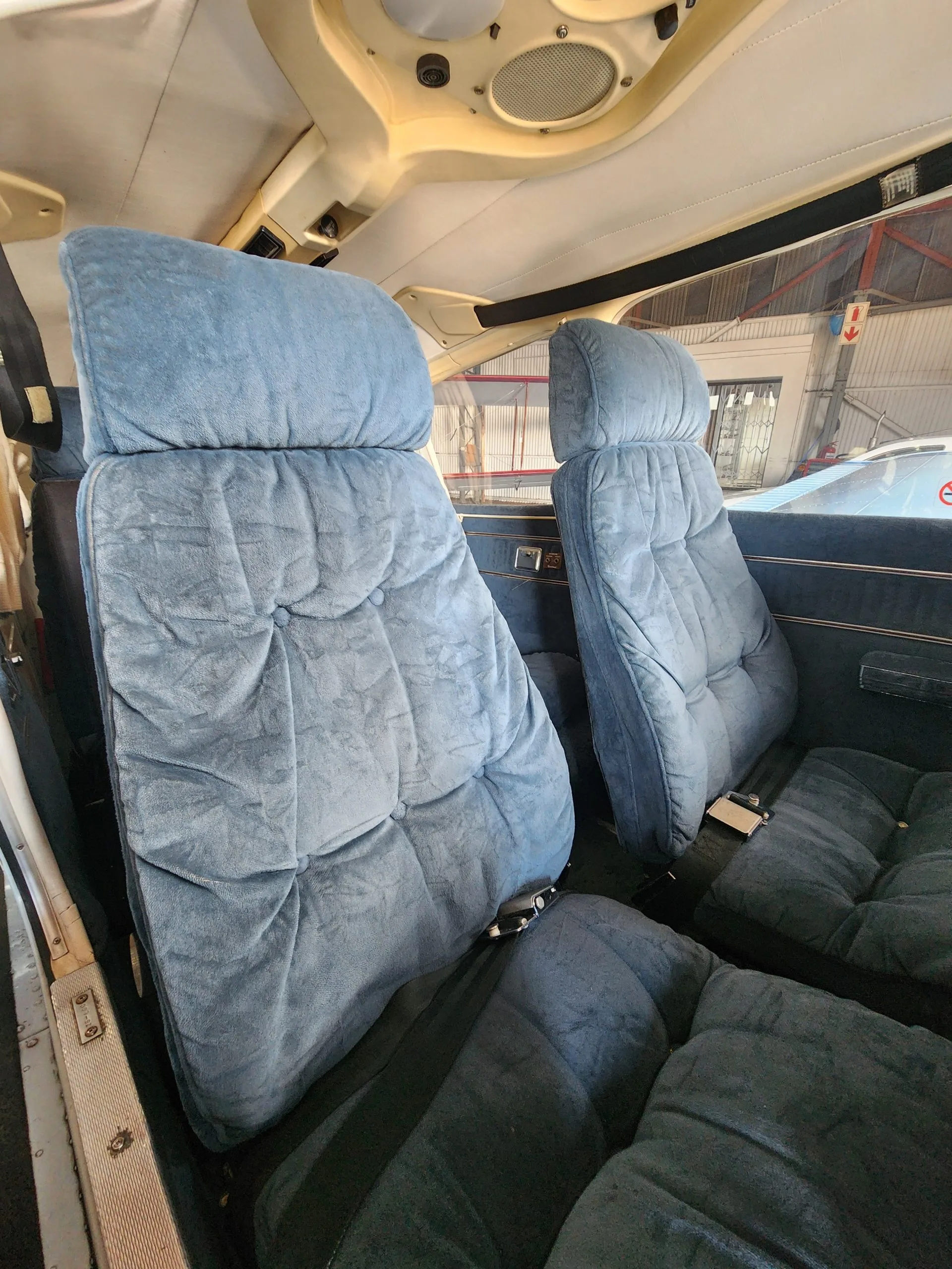 The interior cabin of an aircraft, showing two rows of plush blue fabric seats.