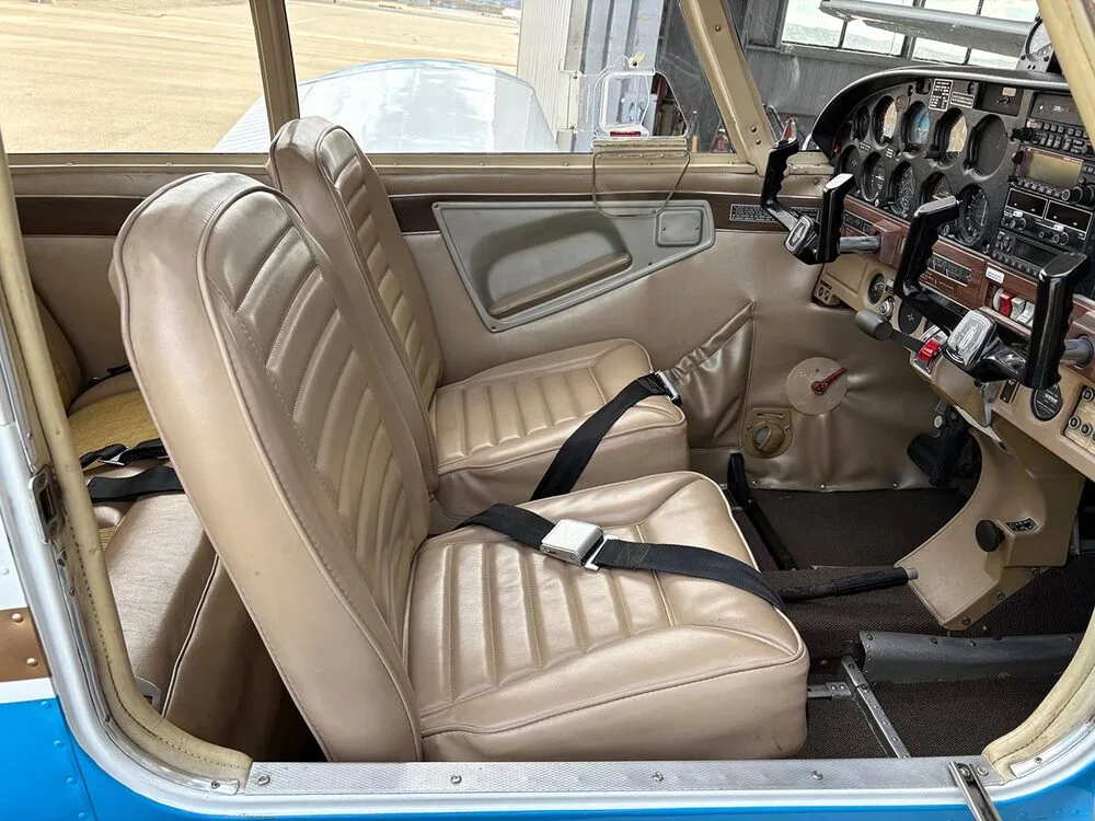 The tan front pilot and co-pilot seats with seatbelts, showing part of the instrument panel on the right.