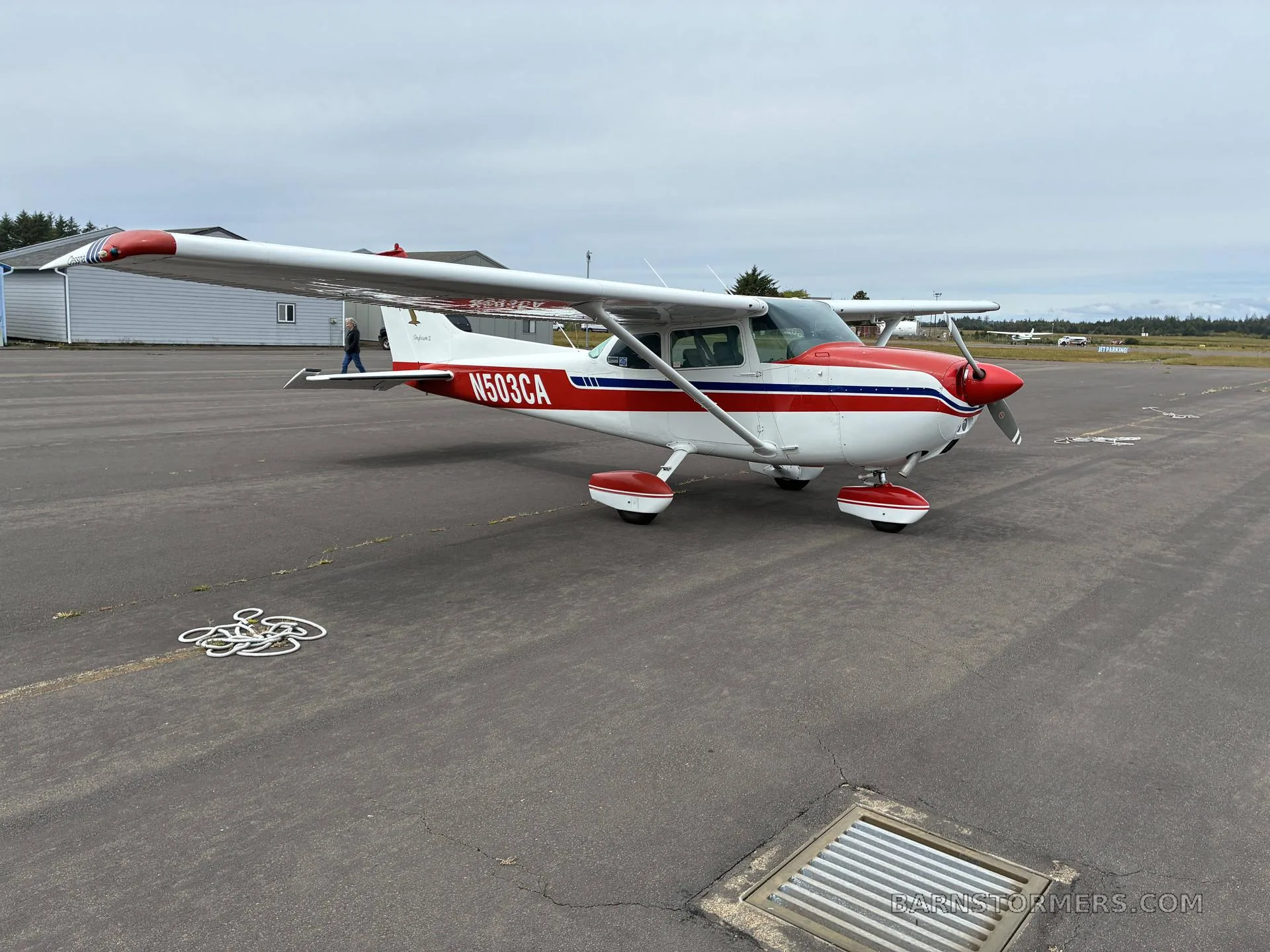 A side view of a white and red Cessna 172 Skyhawk II (N503CA) parked on an asphalt ramp.