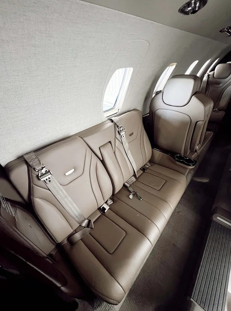 A view of the aircraft's tan leather cabin seats, including a three-person bench and individual seats.