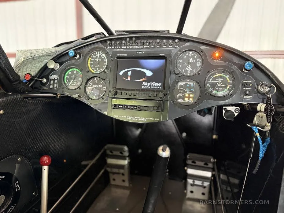 The cockpit instrument panel of an aircraft, featuring analog gauges and a central digital display showing the Dynon SkyView logo.