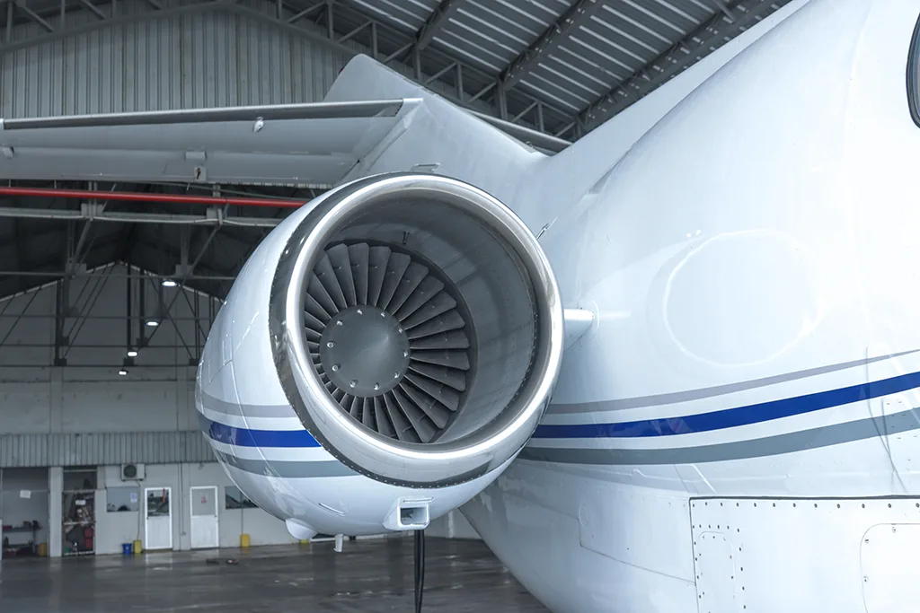 A close-up view of the rear-mounted jet engine on a white aircraft, showing the fan blades.
