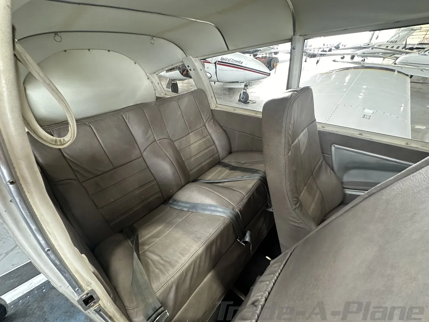 The tan leather rear bench seat of a light aircraft, N3905T, with seatbelts, viewed from the front.