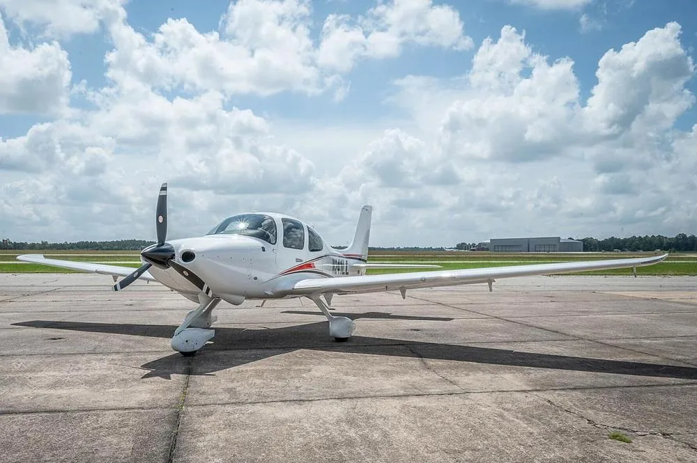 A front three-quarter view of a white Cirrus SR22 aircraft, registration N241LL, parked on an airfield.
