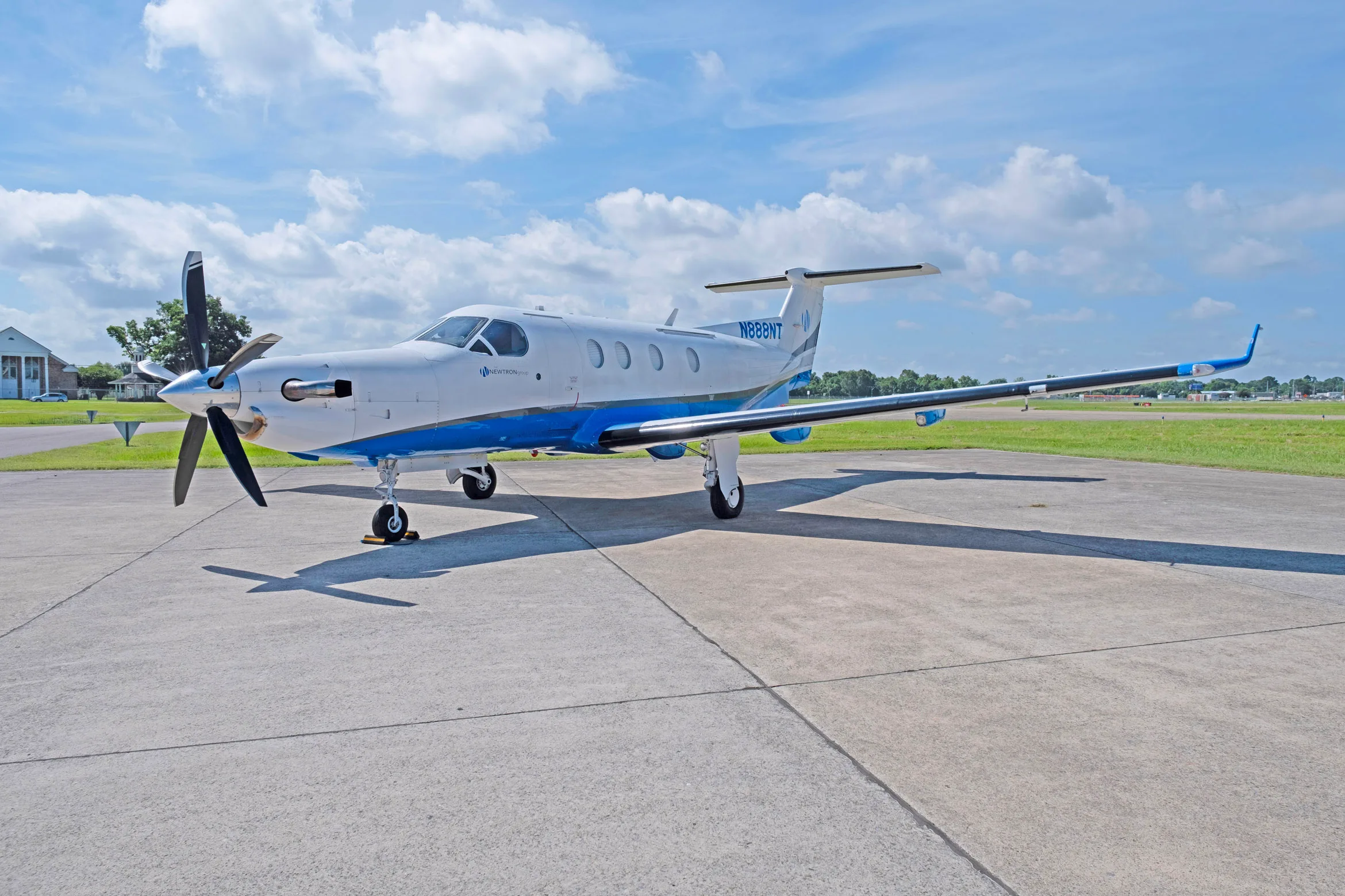 A white and blue Pilatus PC-12 aircraft, tail number N888NT, parked on a tarmac with its propeller visible.