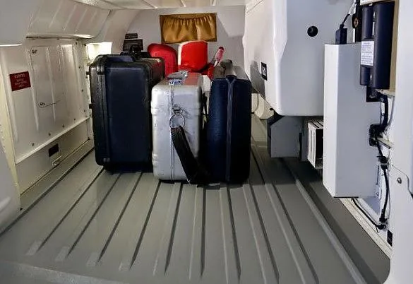 The cargo compartment of an aircraft, showing several pieces of luggage and equipment.