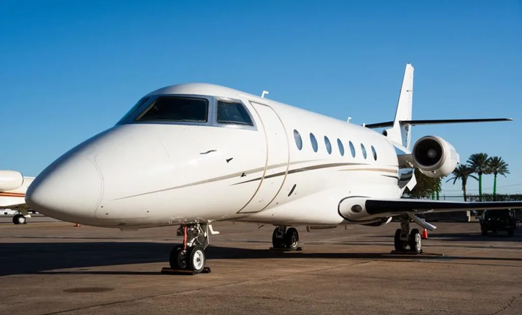 A front-side view of a white Gulfstream G280 business jet with gold and black stripes, registration N280LT, parked on an airport tarmac.
