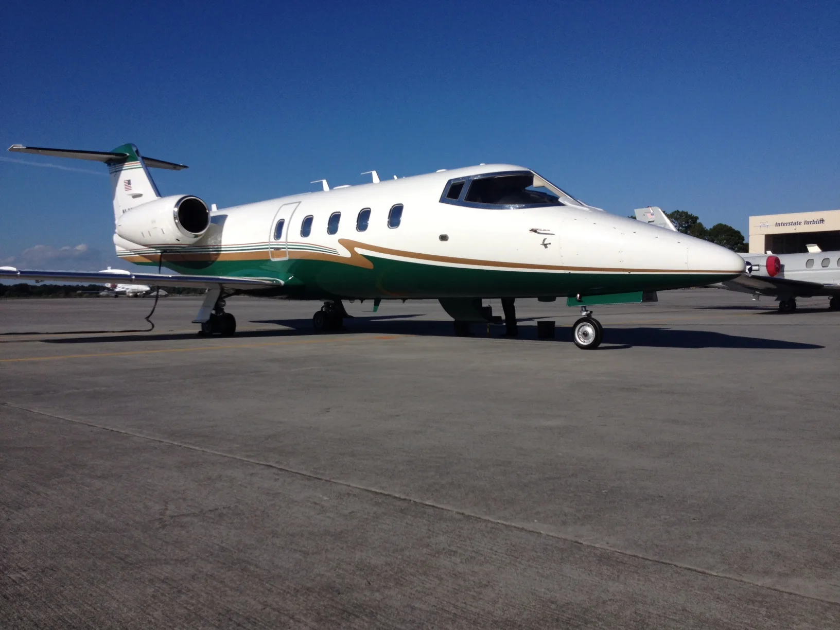 A Learjet 31A with a green and white paint scheme parked on the tarmac.