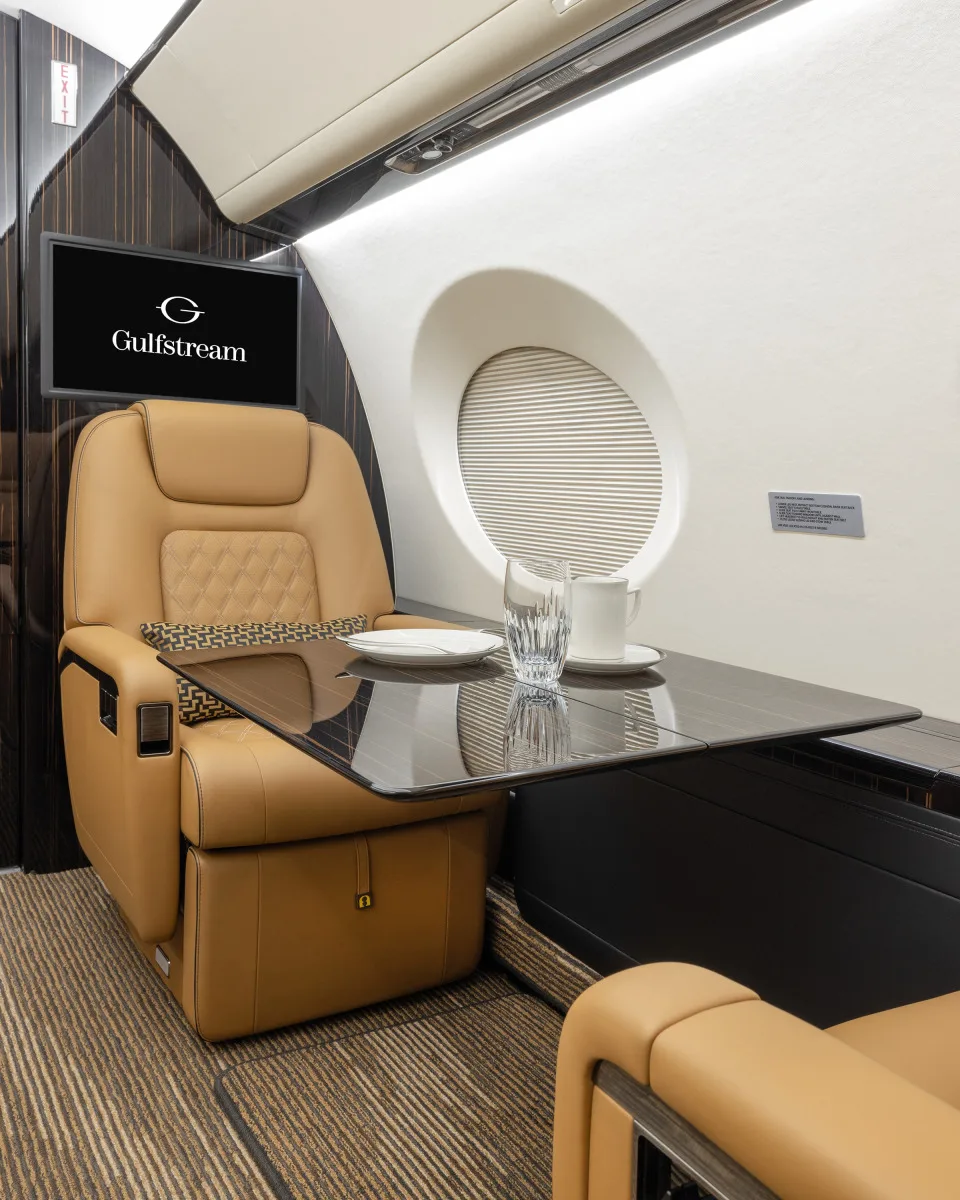 A view of the aircraft's interior with tan leather seats and a table setting.