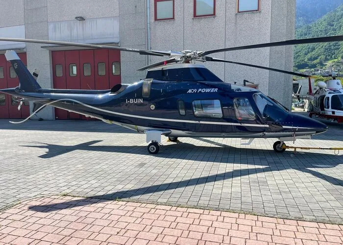 Side view of the I-BUIN Agusta A109 Power helicopter on the ground.