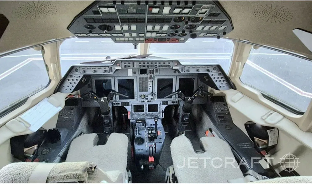 The modern cockpit of a private jet, featuring a complex instrument panel and dual yokes.