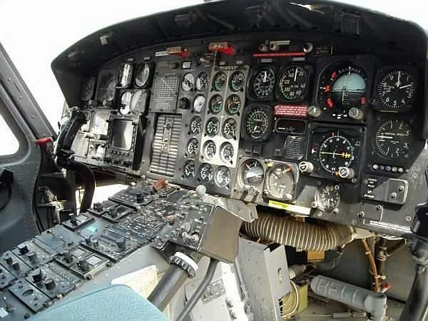 The cockpit of a helicopter, showing a complex instrument panel with many gauges and controls.
