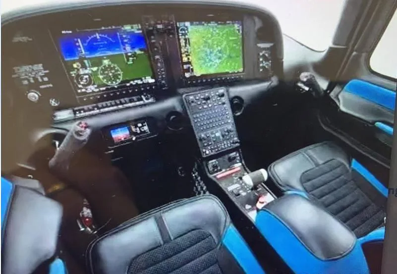 The cockpit of a Cirrus SR22 aircraft, featuring a glass panel display and blue-accented seats.