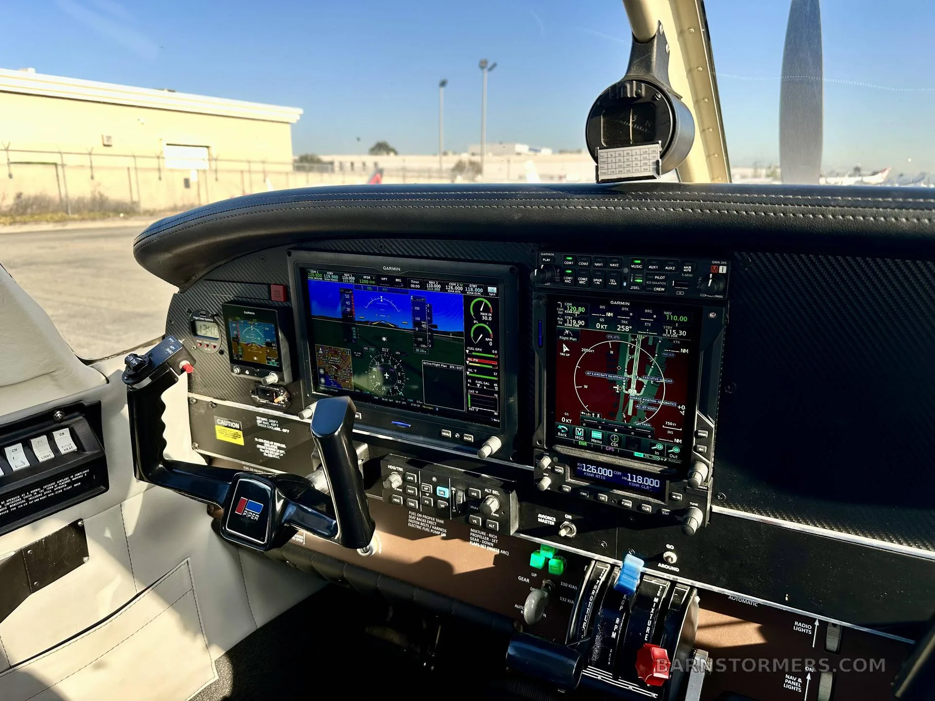 The modern cockpit of an aircraft, featuring two large Garmin glass displays and a control yoke.
