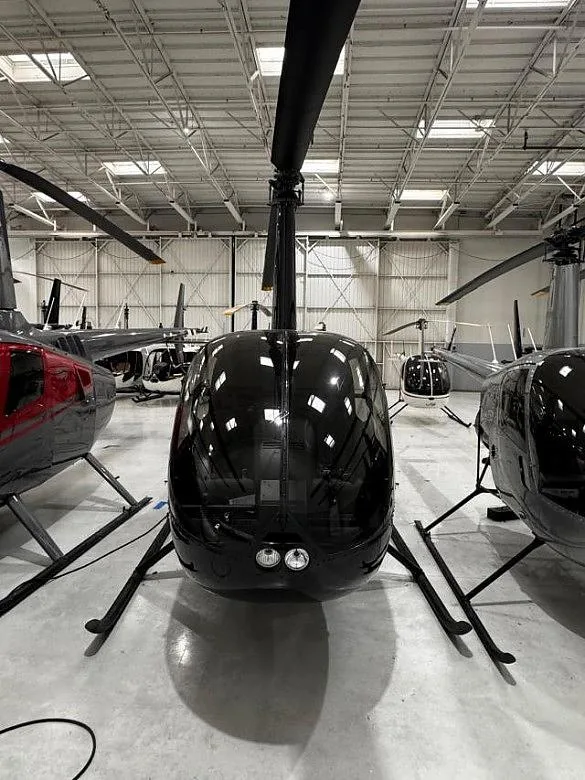 Front view of a black Robinson R-44 Raven I in a hangar.