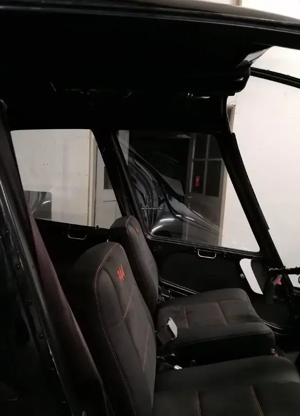 The black leather front seats of a helicopter cabin with red stitching and "R44" logo.
