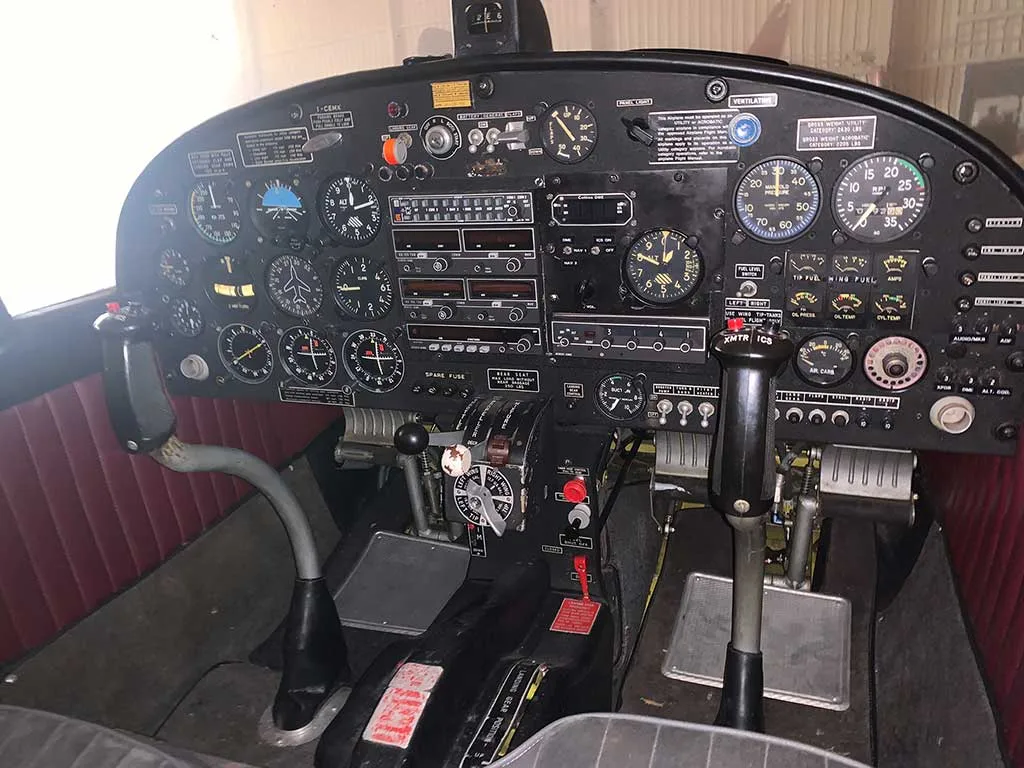 The aircraft cockpit features a black instrument panel with numerous gauges, switches, and a central throttle quadrant.