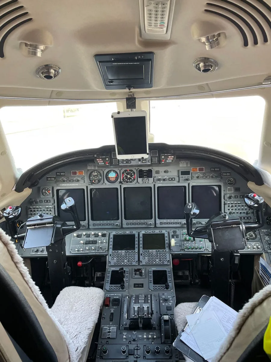 The cockpit of a private jet with multiple screens, controls, and an iPad mounted.