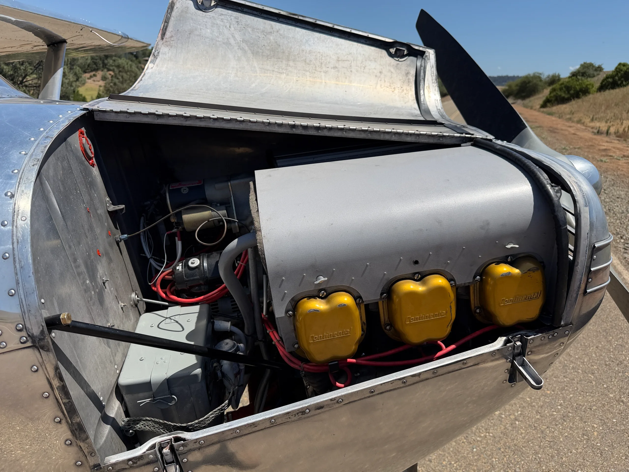 Close-up view of the exposed engine compartment of a polished aluminum Cessna 170 aircraft.