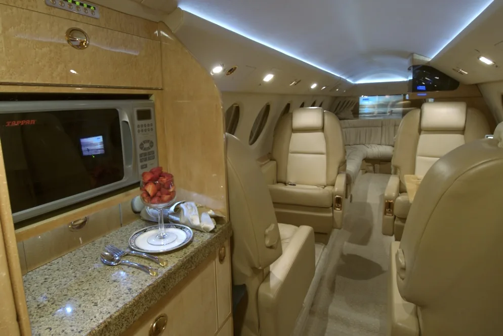 View of the aircraft's interior cabin with seats and a small kitchen area.