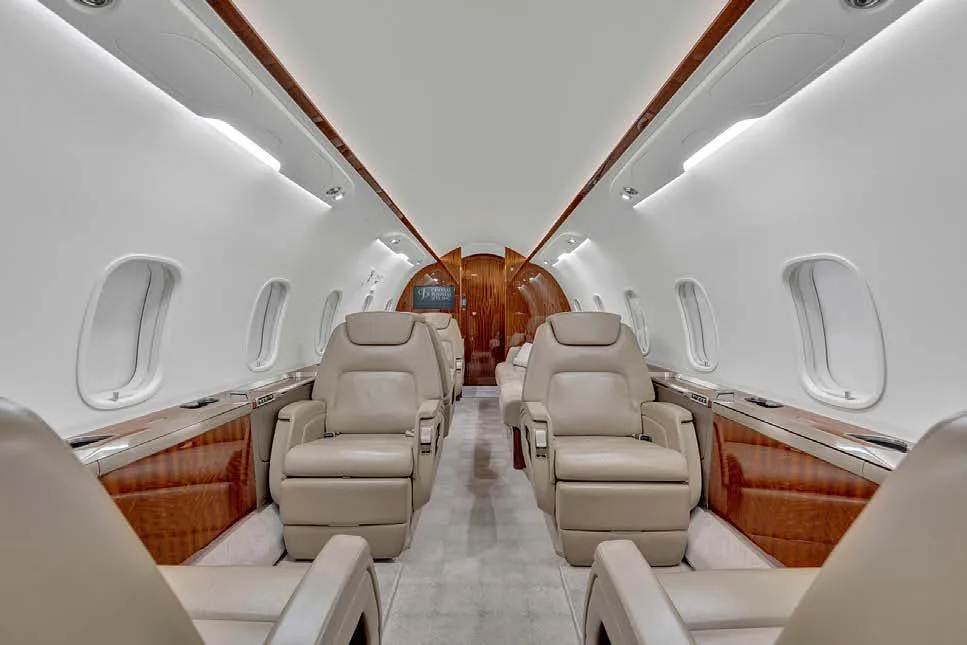 The aircraft cabin interior with light beige leather seats and polished wood accents.