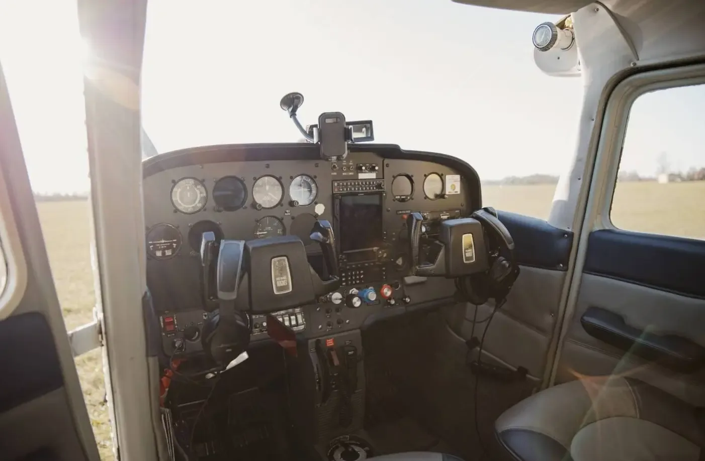 The cockpit of a Cessna aircraft, showing the instrument panel, yokes, and avionics.