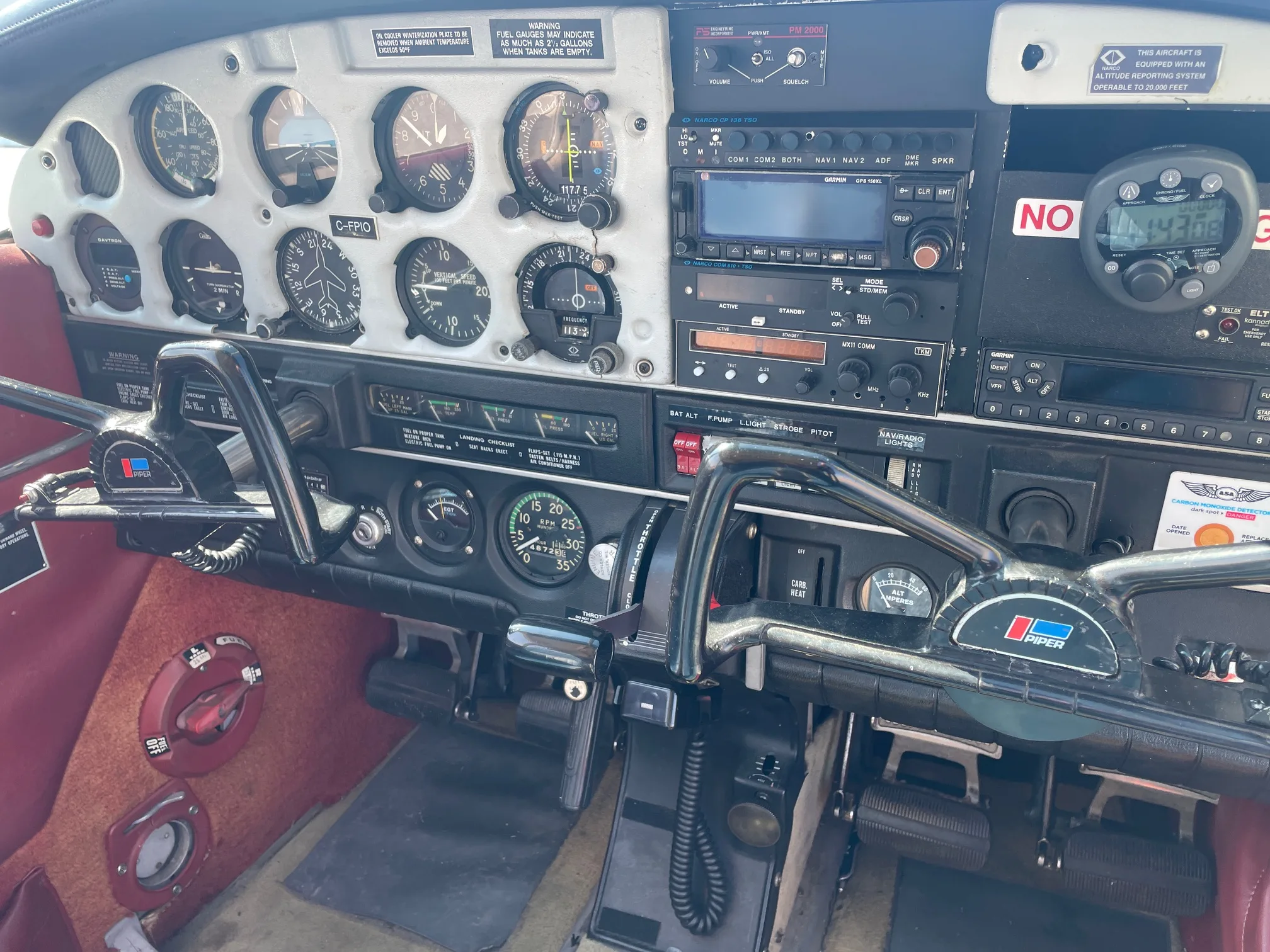 The full cockpit of an aircraft, showing the instrument panel, radio stack, and two control yokes.