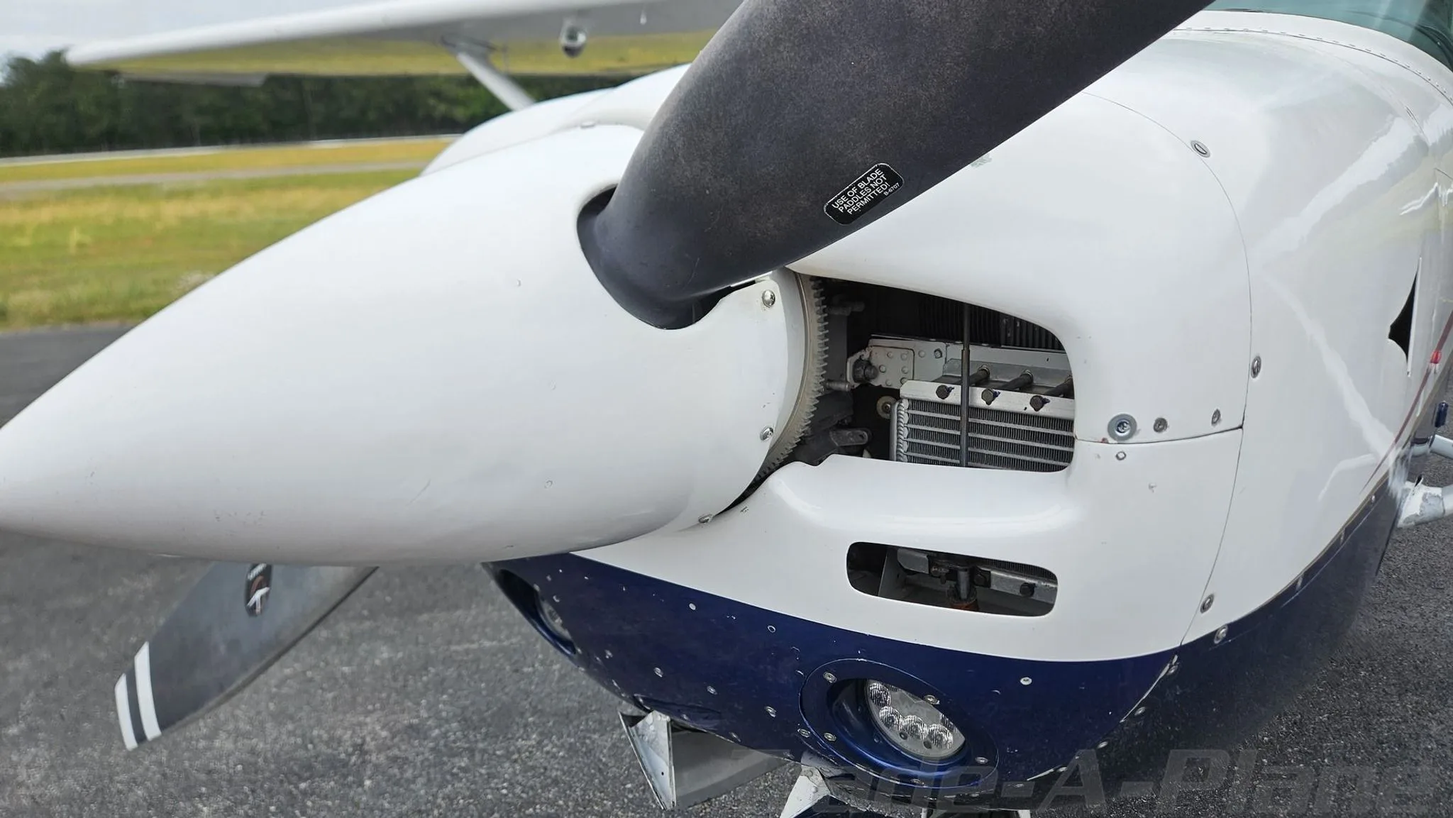 A close-up view of the propeller and nose cone of the white and blue Cessna 182.