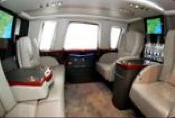Interior view of a helicopter cabin with leather seats and entertainment screens.