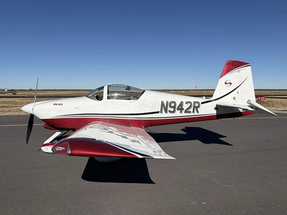 A white and red Van's RV-9A aircraft with registration N942R is parked on an airfield under a clear blue sky.