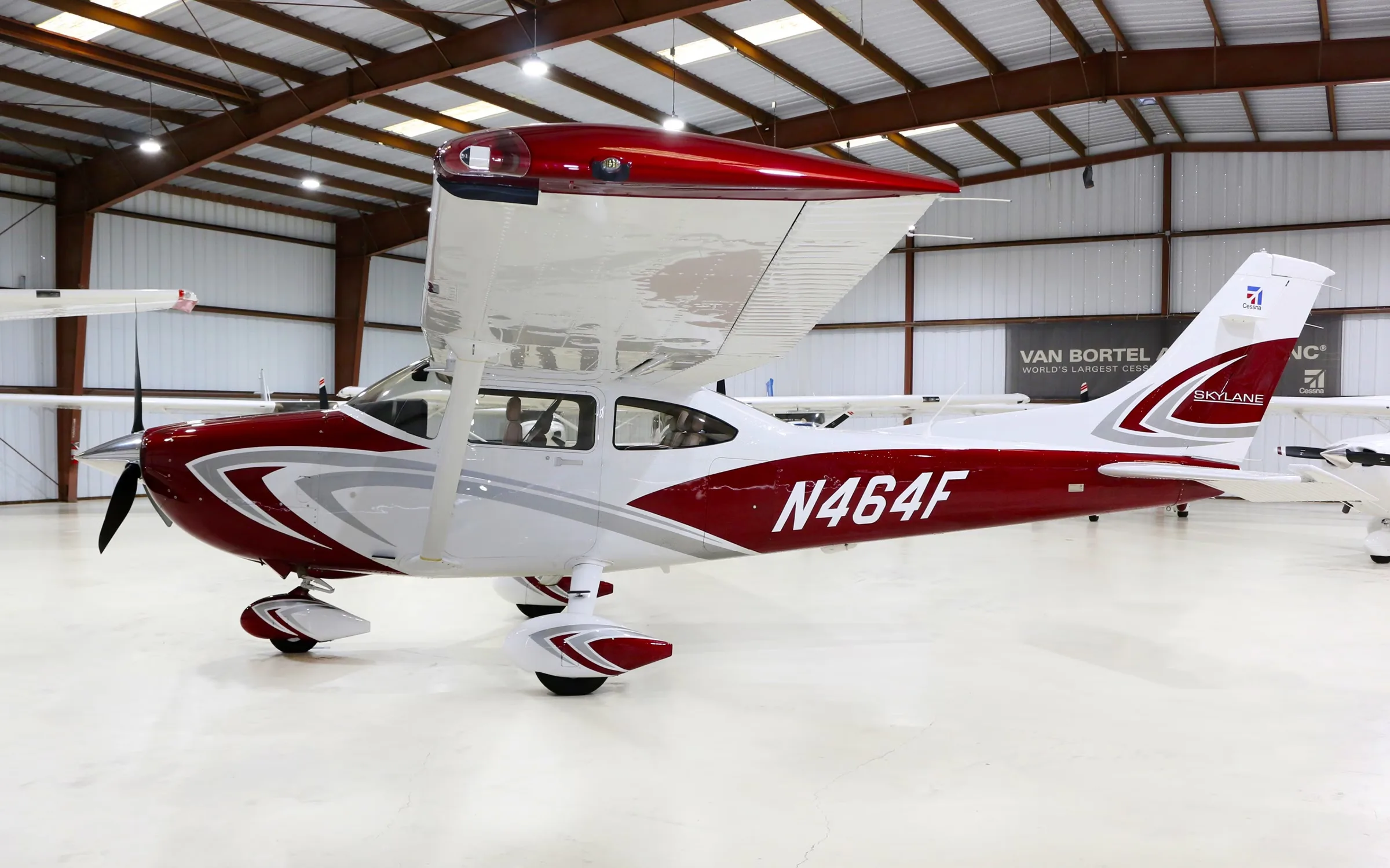 A red and white Cessna Skylane aircraft with registration N464F inside a hangar.