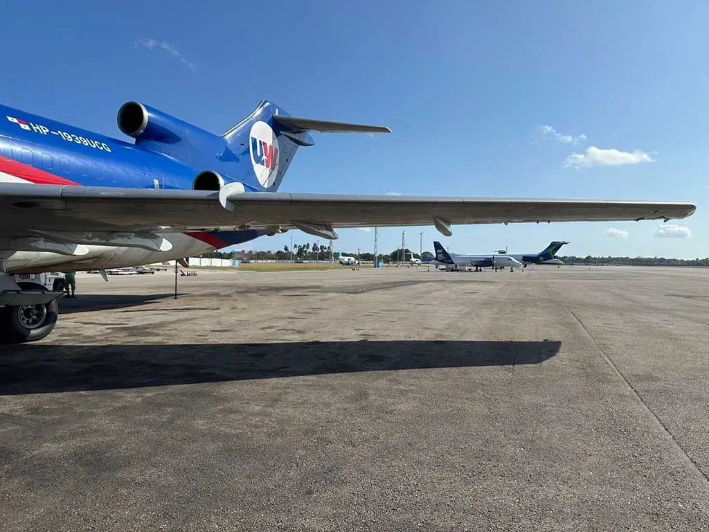 The wing and engines of a UniWorld Air Cargo Boeing 727-200F on the tarmac with other aircraft in the background.
