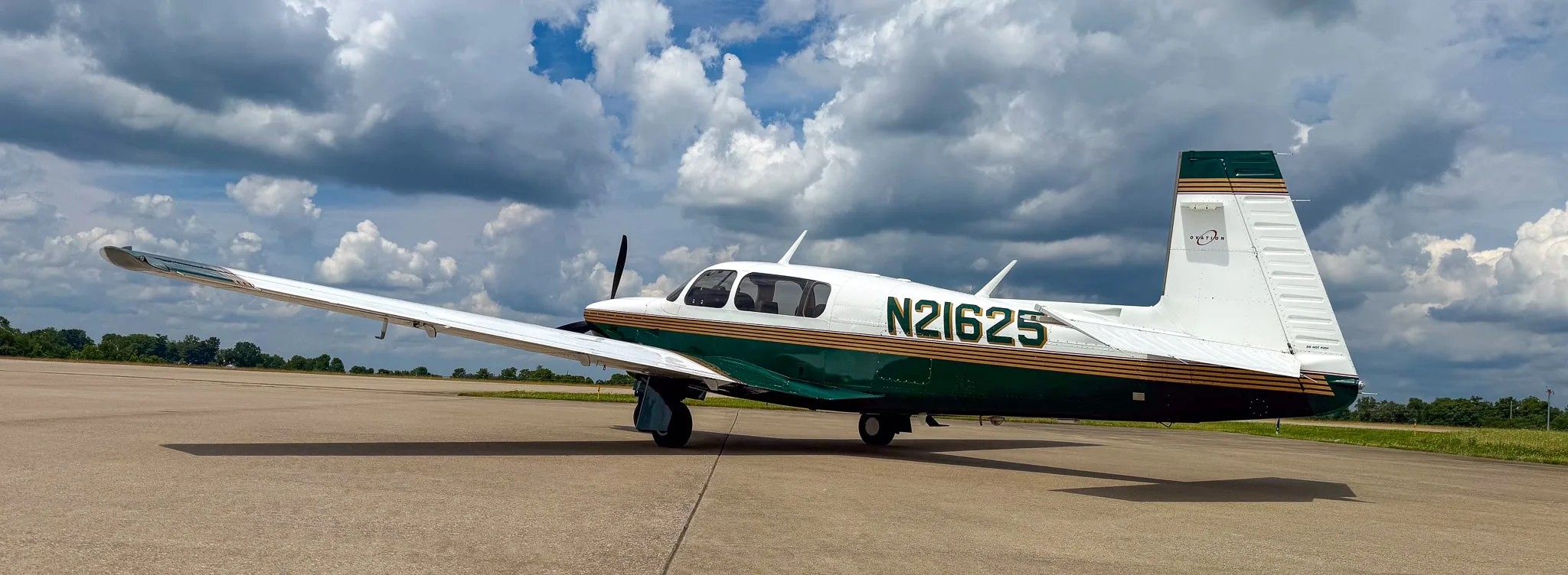 A side view of the white and green Mooney M20 aircraft with registration N21625 on an airfield.