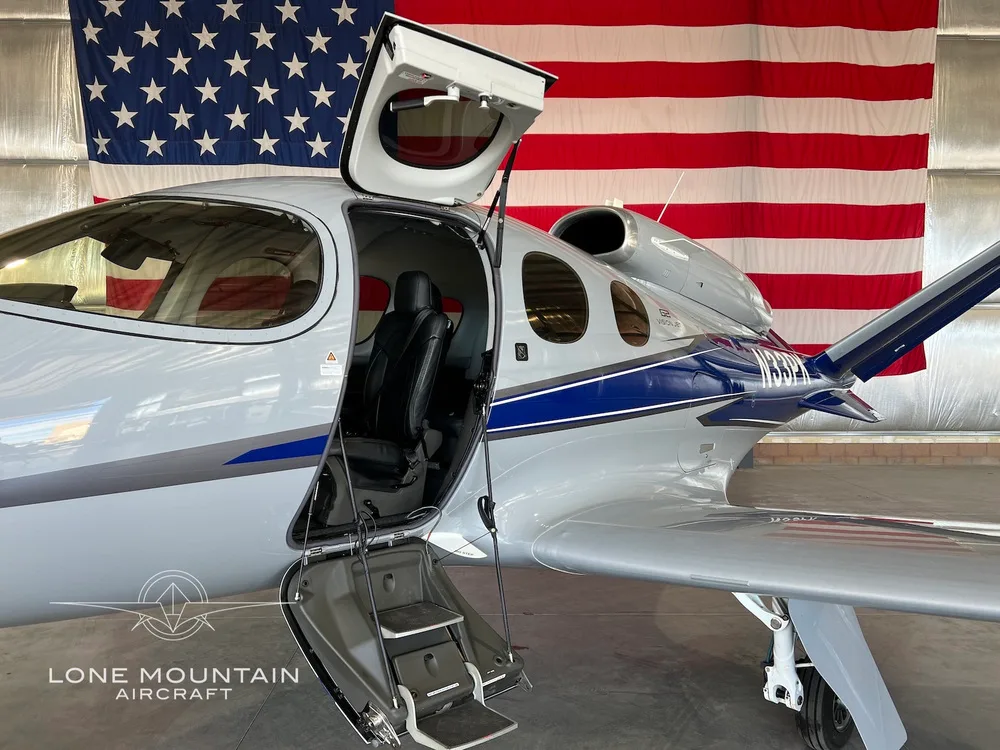 Close-up of the open main door and steps of the Cirrus Vision Jet (N33PK), revealing a black leather seat inside.