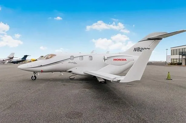 A white HondaJet with registration N829DL is parked on an airport tarmac under a blue sky.